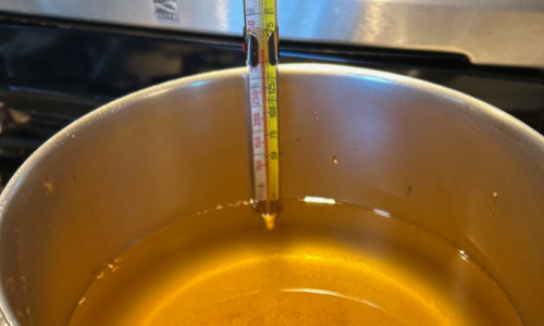 cooking thermometer in a pot of hot oil, monitoring temperature for safe deep frying