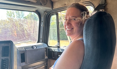 Sister smiling in semi-truck cab on the way to the grain elevator with corn